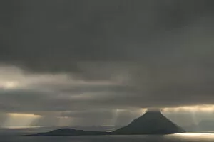 Dramatic mood lighting, low clouds, rays of light falling on the sea, Koltur, Utoyggjar, Faroe Islands, Denmark