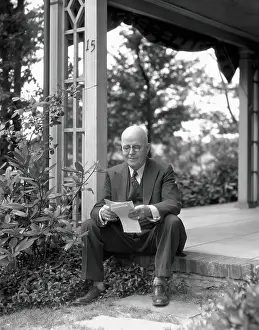 Elderly man, smiling, sitting on front porch step, reading letter