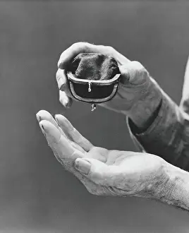 Upside Down Prints: Elderly man's soiled hands turning empty change purse upside down