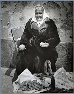 Elderly Woman Seated W/Basket Of Bagels