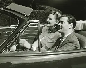 Mid Adult Couple Prints: Elegant couple riding in in convertible car, (B&W)