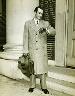 Elegant man checking watch at entrance to building, (B&W)