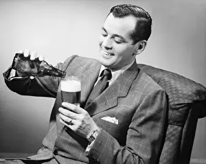 30 35 Years Prints: Elegant man pouring beer from bottle into glass, (B&W)
