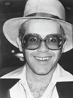 Prints of CIRCA 1975: Pop singer Elton John poses for a portrait wearing a hat and sunglasses with an extra long collar in circa 1975. (Photo by Michael Ochs Archives/Getty Images) Rocket Man: From Stage to Spotlight: Elton John Portrait