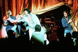 Elvis Presley with a fan in front of the curtains