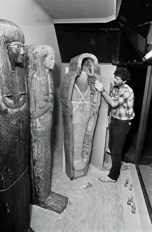 Exhibit Installer Cautiously Adjusting Mummies