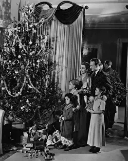 Family with three children (4-9) standing at Christmas tree, (B&W)