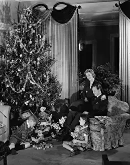 Family with two children (6-9) sitting at Christmas tree, (B&W)