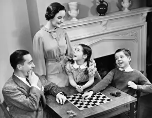 Father Prints: Family with two children (8-9) playing checkers (B&W), elevated view