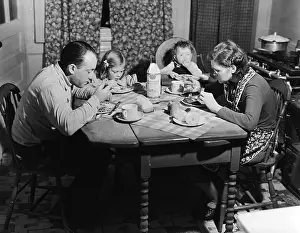 Family Eats Meal At Small Wooden Table