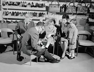 Mature Women Prints: Family of four in shoe shop, salesman fitting shoe on girl as mother