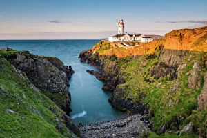 Fanad Head (FA┬ínaid) lighthouse, County Donegal, Ulster region, Ireland, Europe. Lighthouse and its cove at sunset