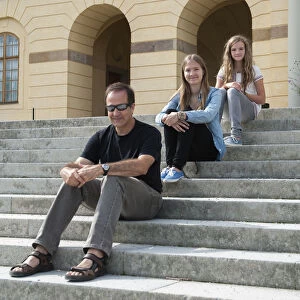A Father And Two Daughters Sitting On Steps At Drottningholm Palace