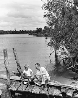 Father and son sitting on dock getting ready to fish