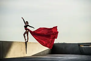 Prints of Young female dancer dancing and jumping in the streets of the city of Lyon in France, with a red / grey color theme The Enchanting Evolution of Ballet: Female dancer dancing in the streets of Lyon, France