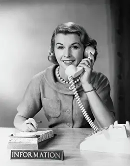One Mid Adult Woman Only Prints: Female telephone receptionist at information desk, answering phone