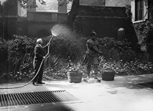 Prints of June 1925: The Commissionaire watering the flowers at Hoares Bank in Fleet Street, London. (Photo by Kirby/Topical Press Agency/Getty Images) Topical Press Agency Prints: Fleet St Gardener