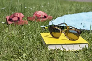 Flip flops, book and sunglasses on grass