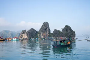 Floating Vietnamese fishing village with rocky coastline