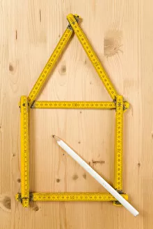 Folding carpenters ruler folded in the form of a house beside a pencil