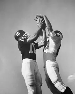 Sports Team Gallery: Two football players jumping for ball at same time