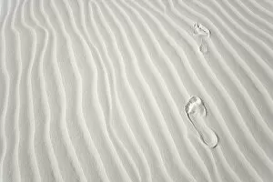 Footprints of barefoot hiker on white gypsum sand dune