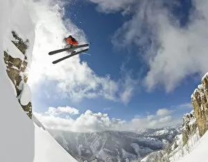 Freestyle skier spinning while jumping off of cliff