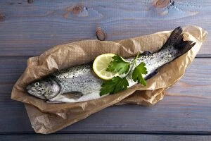 Fresh brook trout in baking paper on a wooden surface