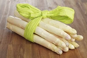 Fresh unpeeled white asparagus, wrapped with a green ribbon