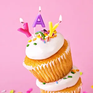 Images Dated 28th September 2018: Frosted cupcakes with sprinkles and candles on pink background with confetti