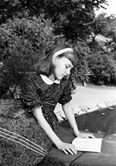 Headband Prints: Girl (12-13) reading book, sitting on bridge in park