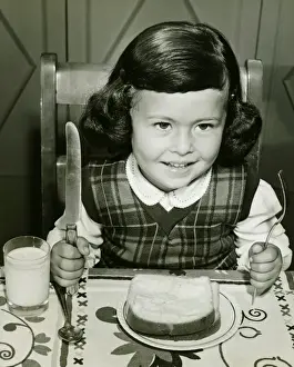 Wavy Hair Prints: Girl (4-5) having meal, holding fork and knife, (B&W)