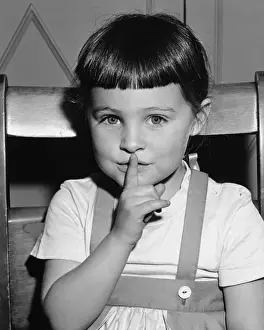 Girl (4-5) holding finer on mouth, (B&W), portrait