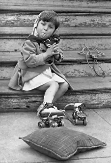 Headscarf Prints: Girl (4-5) in roller skates sitting on stairs and sticking out tongue