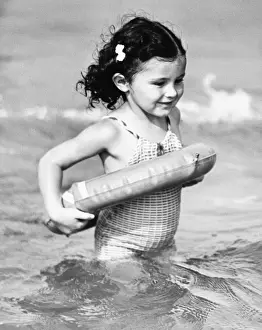 Weekend Activities Prints: Girl (4-5) standing in water with inflatable ring (B&W)