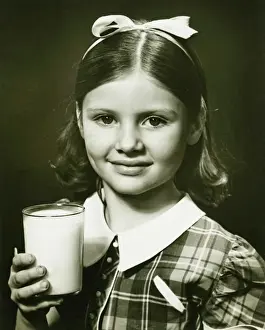 Ribbon Sewing Item Prints: Girl (6-7) holding glass of milk, posing in studio, (B&W), close-up, portrait