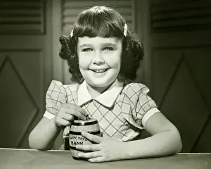 Savings Prints: Girl (6-7) putting coin into money-box, (B&W), (Close-up), (Portrait)