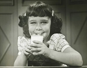 Girl (6-7) sitting at table, drinking milk, (B&W), (Close-up), (Portrait)