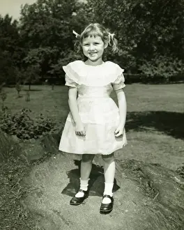 Girl (6-7) in white dress posing in park, (B&W), (Portrait)