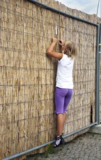 Fence Prints: Girl, 8, looking curiously through an opening in a straw fence