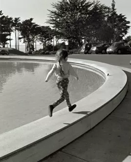 Girl running along edge of fountain