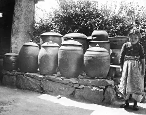 Prints of A small girl stands next to several large ceramic pickle jars, Korea, early 20th Century. (Photo by Frederic Lewis/Getty Images) Urban Echoes of America’s Golden Age: Girl w/ Korean pickle vessels