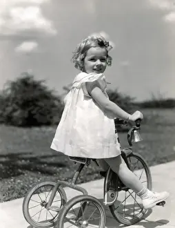 Sidewalk Prints: Girl wearing summer dress, riding tricycle down sidewalk