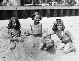 Digging Prints: Three girls (4-5) playing in sand on beach