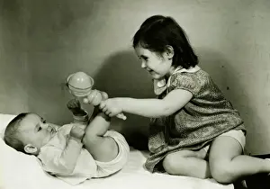 6 11 Months Prints: Two girls (6-12 months) (3-4) playing with rattle, (B&W)