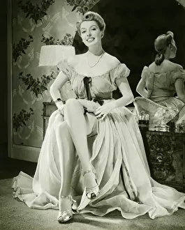 Glamorous woman in evening gown showing legs, (B&W), portrait