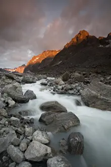 Flowing Prints: Greenland, Itilleq, setting sun lighting mountain peaks above mountain stream along Itilleq Fjord
