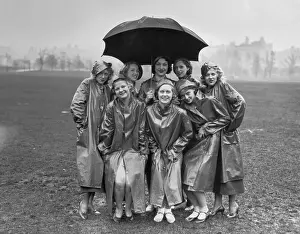 Raincoat Prints: Group of young women standing on field under umbrella