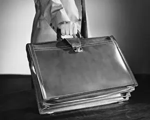 Picking Up Prints: Hand shot of man picking up briefcase