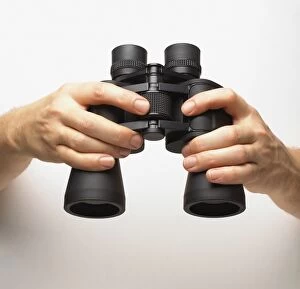 Images Dated 10th March 2008: Hands holding binoculars, finger turning central knob, adjusting focus